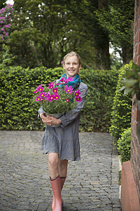在花园里抱着种植盆的女孩肖像图片