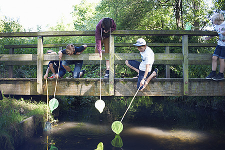 男孩在桥上用渔网捞鱼图片