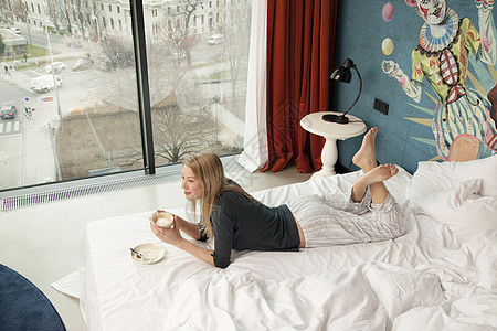马来西亚酒店年轻女性躺在床上喝咖啡背景