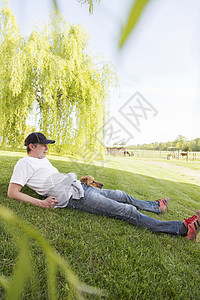 男人和狗躺在草地上图片