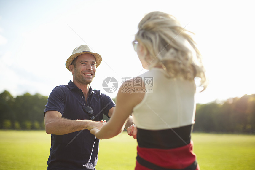 草坪上手牵手的年轻夫妇图片