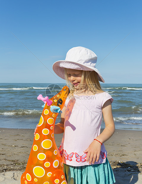沙滩上拿着充气长颈鹿的女孩图片