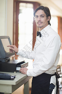 在餐馆现金登记簿上使用触摸屏的服务员 图片