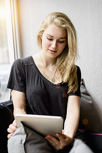 年轻妇女在窗口座位上使用平板电脑图片