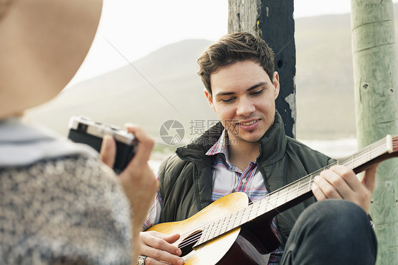在南非西开普市敦海岸码头为女友演奏音乐吉他的年轻人图片