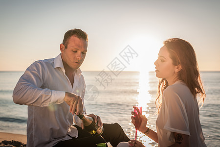 在海滩上喝香槟的年轻夫妇图片