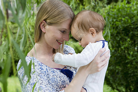 花园里抱着女婴的年轻母亲图片
