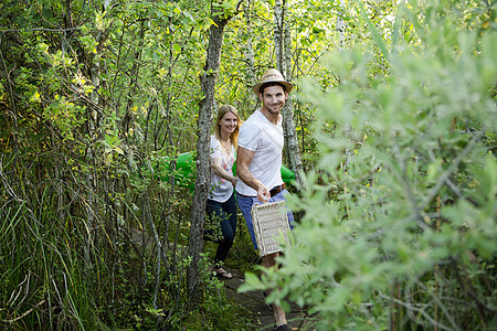 夫妇拿着野餐篮子行走在树林中图片