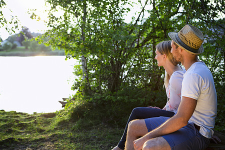 年轻夫妻坐在湖边观看日落图片