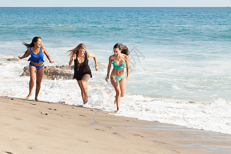 三名年轻妇女在美国加利福尼亚州马里布海滩上奔跑图片