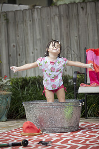 女孩在花园的浴盆中双臂伸展图片