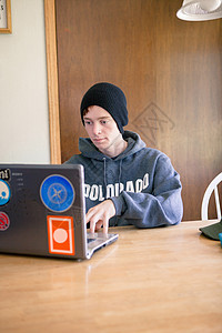 使用笔记本电脑坐在餐厅桌上工作的少年男孩图片