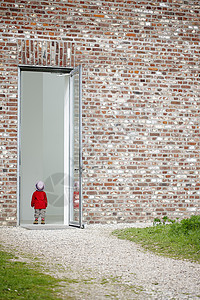 小女孩站在砖墙的门前图片
