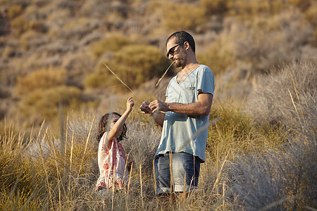 父亲和女儿在山坡玩长草图片