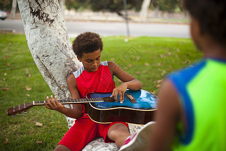 两兄弟坐在公园树枝上弹吉他图片