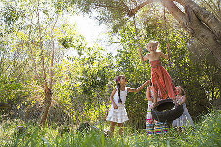 四个女孩在花园轮胎上玩耍图片