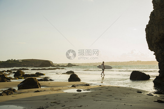 成年男子拿着冲浪板走向海洋图片
