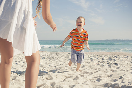 海滩上与年轻儿子一起玩耍的中年母亲图片