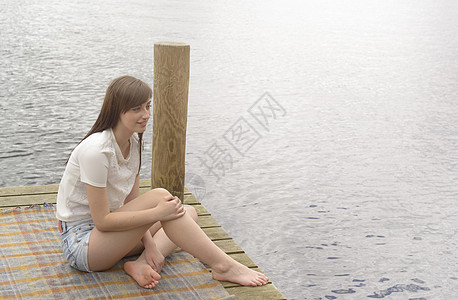 坐在湖边码头上的年轻女子图片