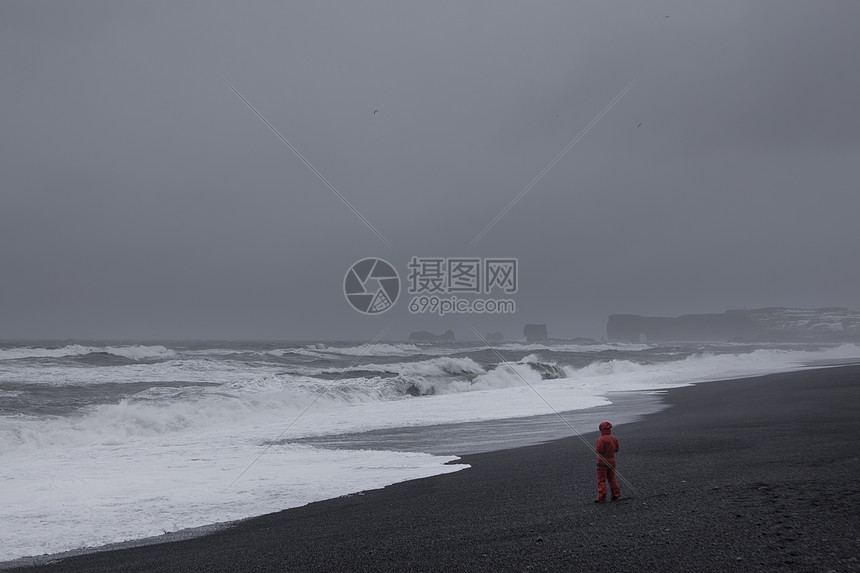 穿红衣服的人站在沙滩上面对大海图片