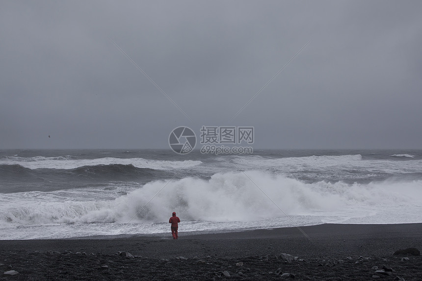 穿红衣服的人站在沙滩上面对大海图片