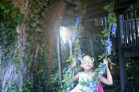 年轻女孩穿着华丽的服装坐在树上摇摆图片