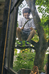 两个男孩在小屋窗外的树上玩图片