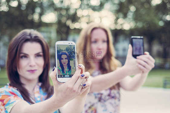 两个年轻女朋友一起在智能手机上自拍图片