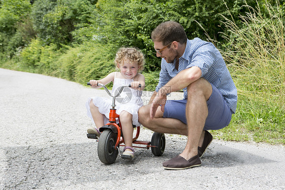 女孩和父亲一起骑三轮车图片