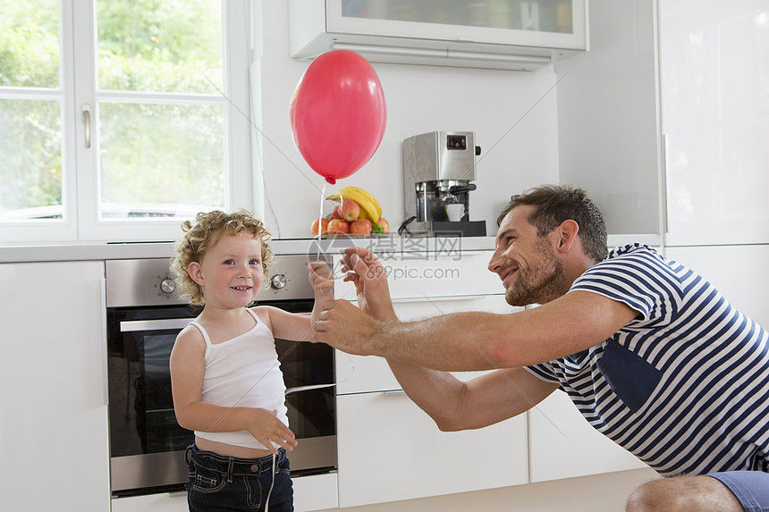 女孩带着气球和父亲在厨房图片