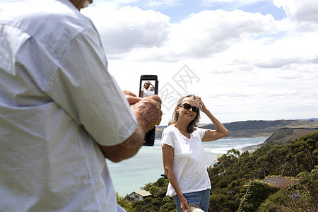丈夫拍照妻子背景为海洋新西兰拉格图片