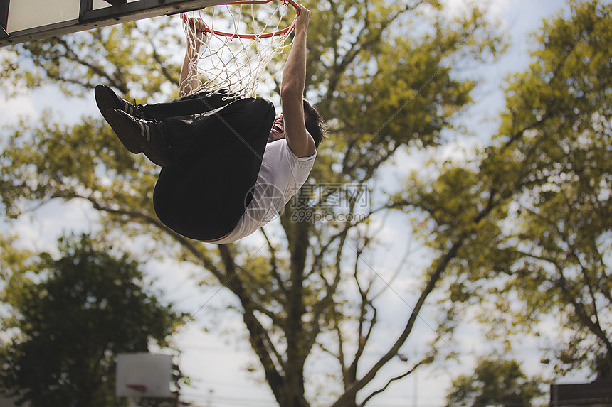 从篮球圈挂起的年轻男篮球低角度视图图片