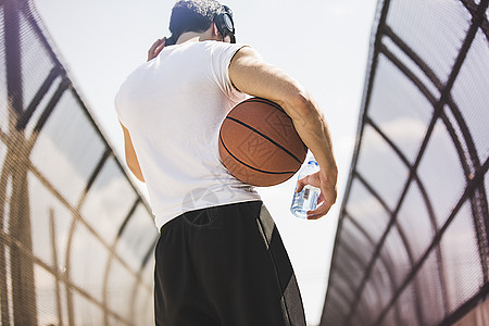 年轻男篮球运动员抱着篮球走在路上图片素材