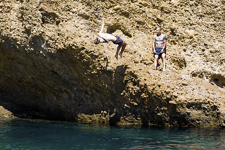 两名年轻人从法国马赛的岩石跳入海中图片
