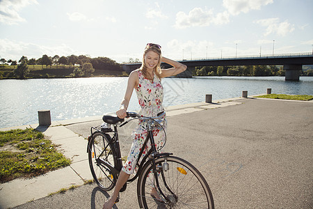 在纳多瑙河岛边骑自行车的年轻女人图片