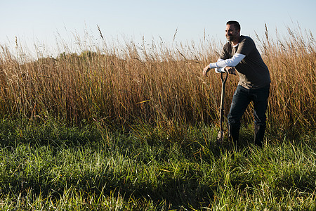美国密苏里普拉茨堡长草区的依靠锄头的农民图片