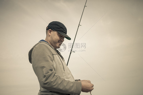 在海边钓鱼的成年男性图片