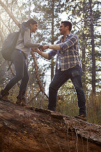 森林里年轻男人帮助女友行走图片