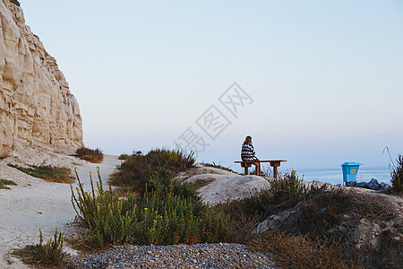坐在长椅上眺望大海的年轻女子高清图片