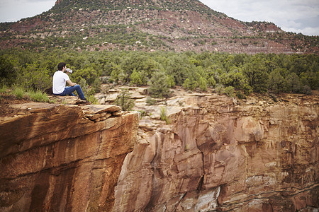 坐在岩石上看风景的青年男性图片