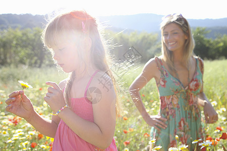 母亲和女儿在草地上采摘野花图片