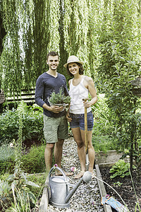 一对夫妇在花园里拿着花盆和铲子图片