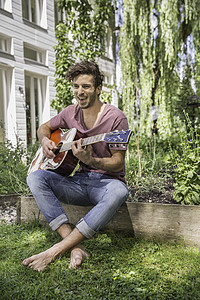 年轻人在花园里弹吉他图片