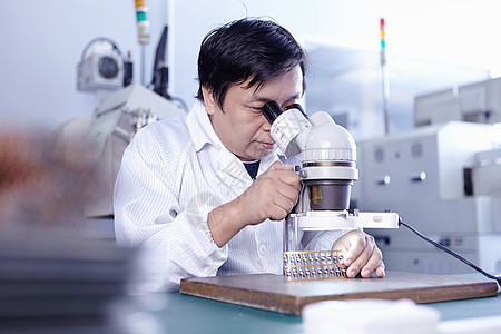 LED工厂使用显微镜的技术员背景图片