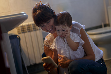 成年女性抱着婴儿玩智能手机图片