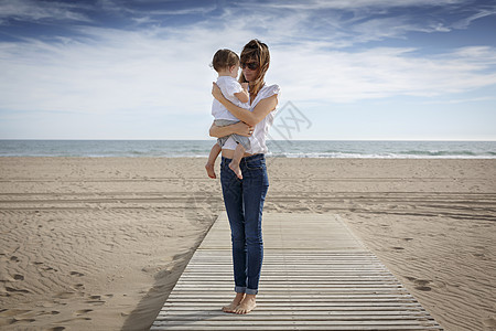 西班牙加泰罗尼亚海滩上抱着孩子的年轻女性图片