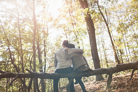 一对夫妇坐在树林中倒下的树上图片