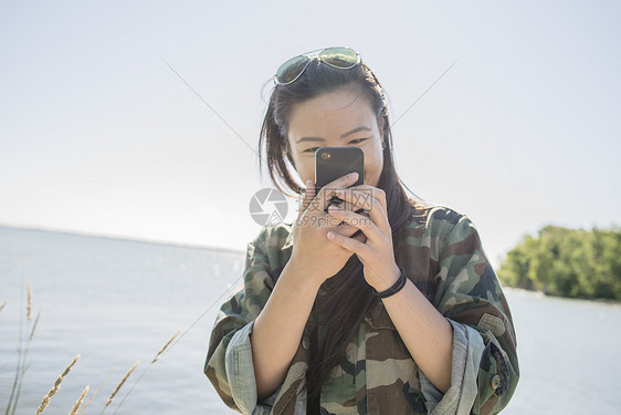 在海边使用智能手机的中年妇女图片