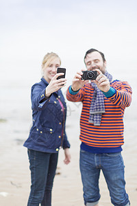 情侣们在户外用相机和智能手机拍照图片