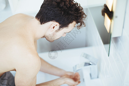 青年男子在浴室洗手池中洗手图片